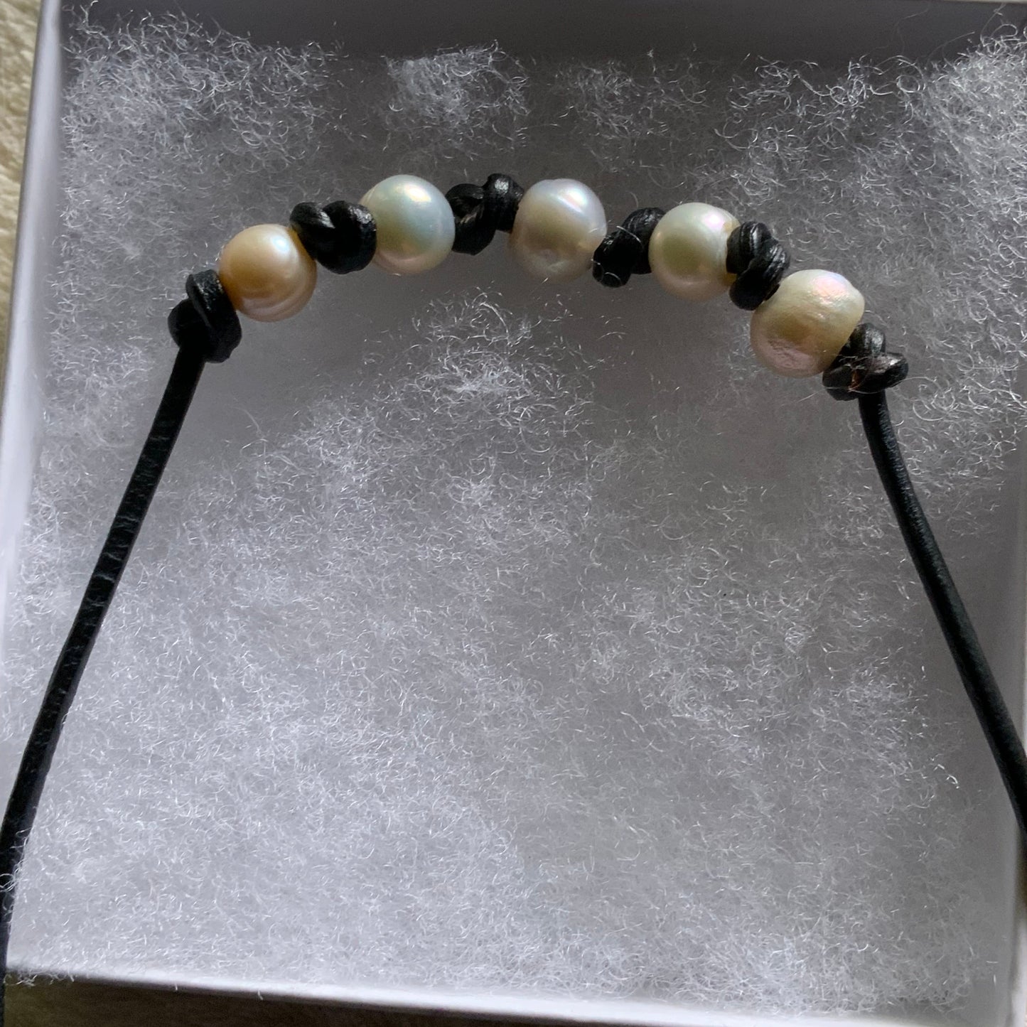 Necklace with pearls and black leather on a textured surface
