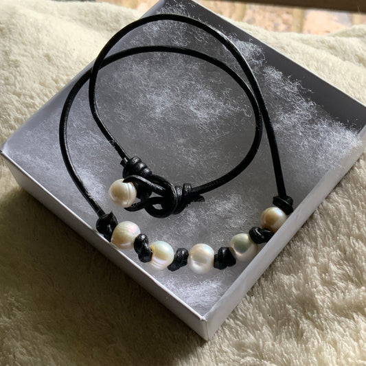 Black and white pearl necklace on a gray card with a textured beige surface background
